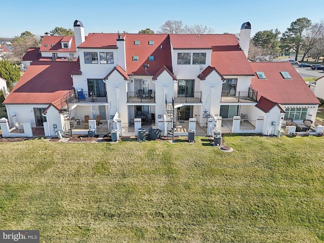 back of property featuring fence, a yard, stucco siding, a chimney, and a residential view