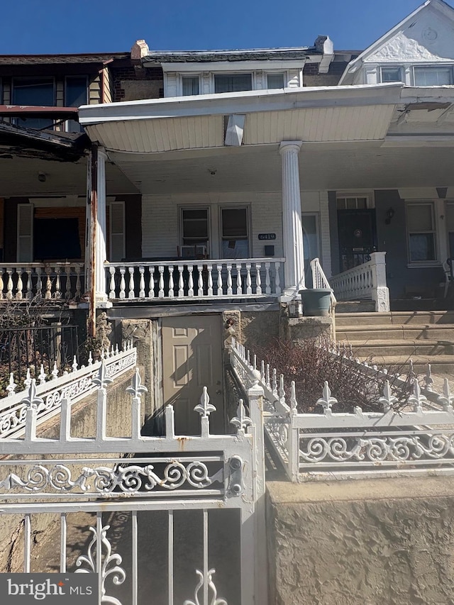 townhome / multi-family property featuring a porch, fence, and brick siding