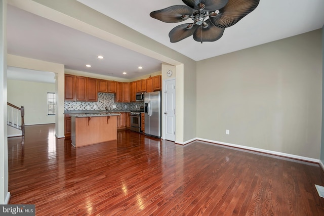 kitchen featuring a breakfast bar, dark wood-style flooring, backsplash, and stainless steel appliances