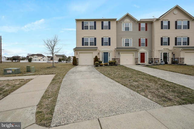 view of property featuring a garage, stone siding, a front lawn, and driveway