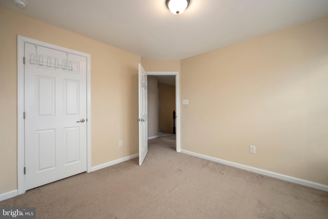 unfurnished bedroom featuring baseboards and light carpet