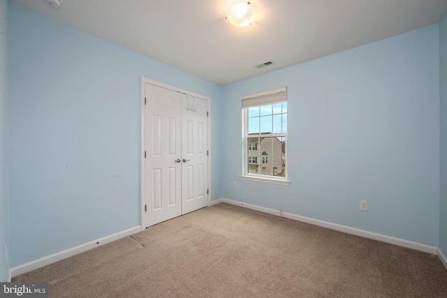 unfurnished bedroom with a closet, visible vents, baseboards, and carpet floors