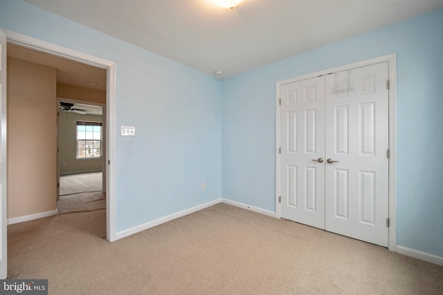 unfurnished bedroom featuring light carpet, a closet, and baseboards