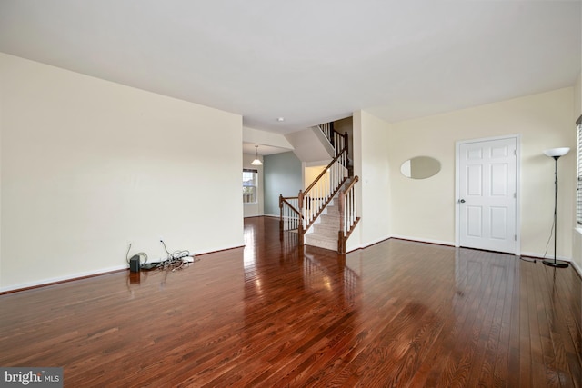 unfurnished living room with stairs, baseboards, and hardwood / wood-style floors