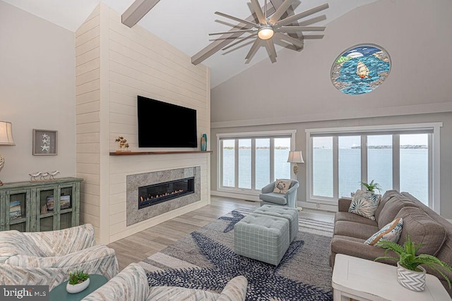 living room featuring high vaulted ceiling, a glass covered fireplace, and wood finished floors