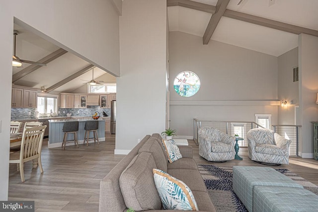 living area with light wood-type flooring, visible vents, ceiling fan, and baseboards