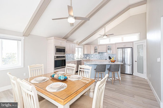 dining area with lofted ceiling with beams, light wood finished floors, baseboards, and a ceiling fan