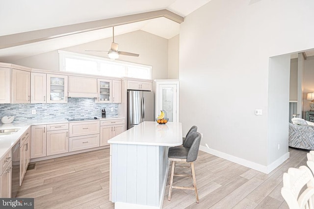 kitchen with light wood finished floors, appliances with stainless steel finishes, a kitchen breakfast bar, and backsplash