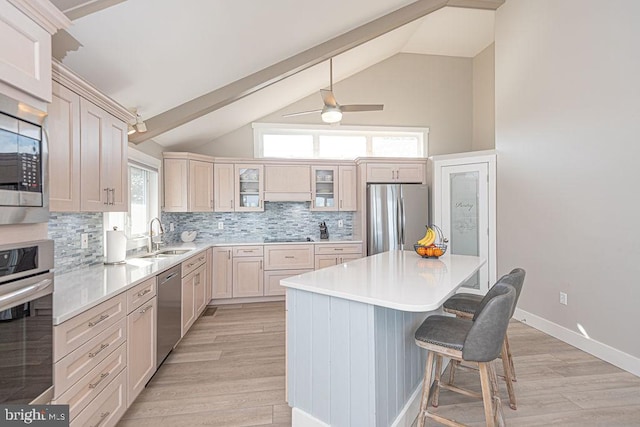 kitchen featuring a sink, a kitchen breakfast bar, appliances with stainless steel finishes, light wood-type flooring, and glass insert cabinets