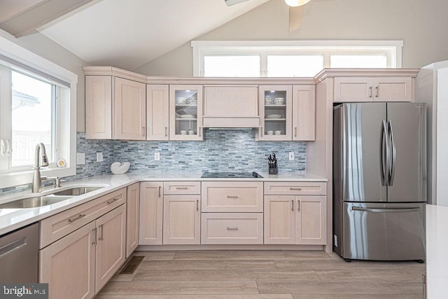 kitchen with stainless steel appliances, vaulted ceiling, light countertops, and a sink