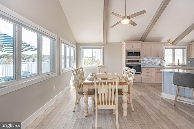 dining room featuring vaulted ceiling with beams, a ceiling fan, light wood-style flooring, and baseboards