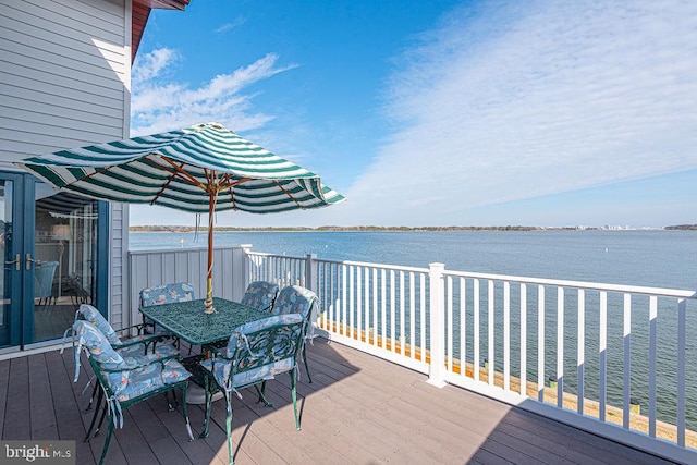 wooden terrace with a water view and outdoor dining area