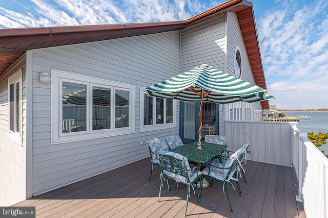 deck with outdoor dining area and a water view