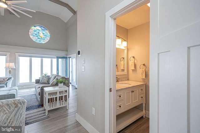 bathroom featuring high vaulted ceiling, wood finished floors, vanity, and baseboards