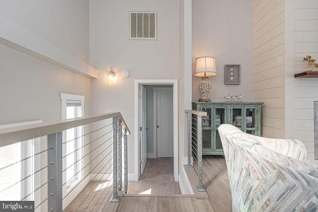 interior space featuring a towering ceiling, baseboards, visible vents, and wood finished floors