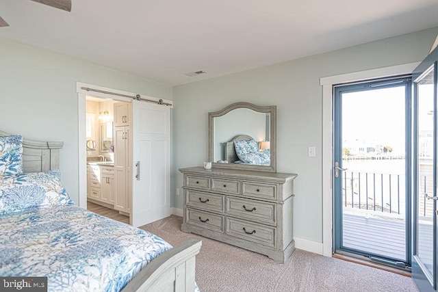 bedroom with a barn door, visible vents, connected bathroom, light colored carpet, and access to outside