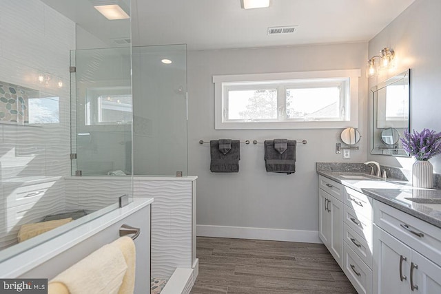 full bathroom featuring baseboards, visible vents, wood finished floors, walk in shower, and a sink