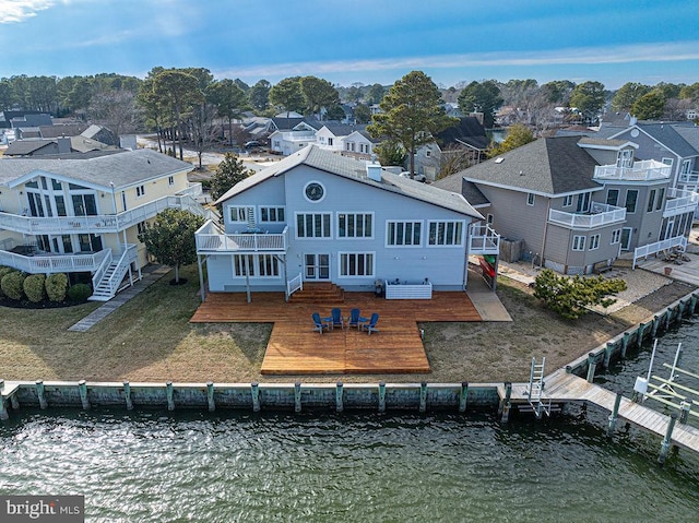 rear view of property with a lawn, a deck with water view, a balcony, and a residential view