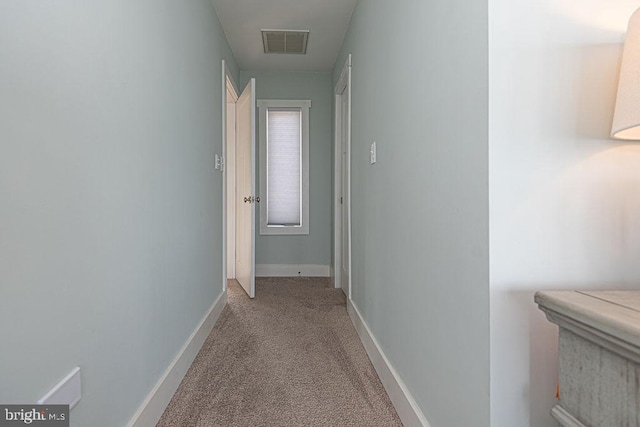 hall with carpet floors, visible vents, and baseboards