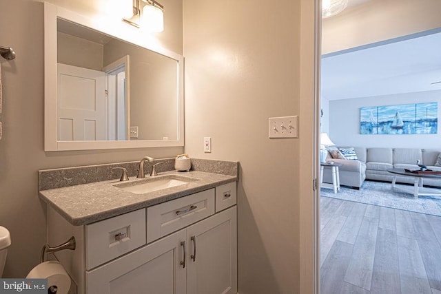 bathroom featuring toilet, wood finished floors, and vanity