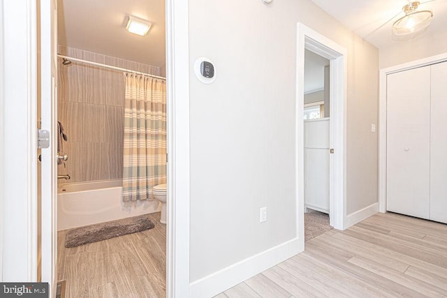 full bathroom with toilet, shower / bath combination with curtain, baseboards, and wood finished floors