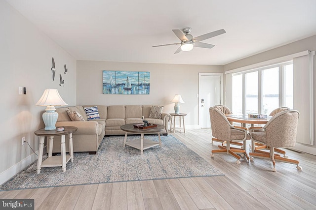 living area featuring ceiling fan, baseboards, and wood finished floors