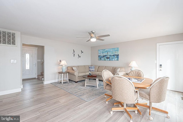 living area featuring light wood-type flooring, baseboards, and a ceiling fan