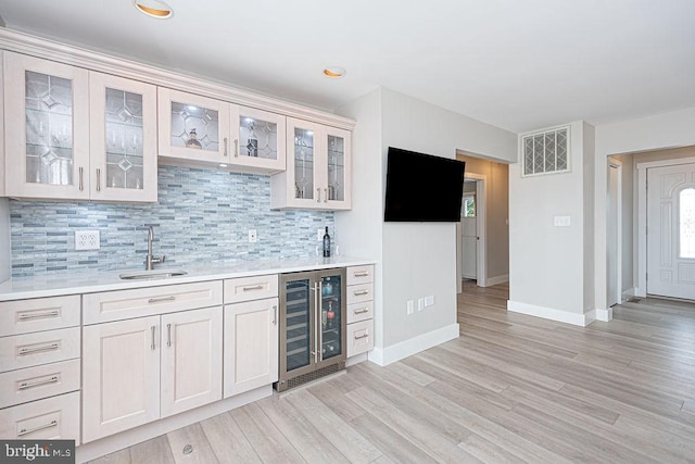 bar with wine cooler, indoor wet bar, visible vents, backsplash, and a sink