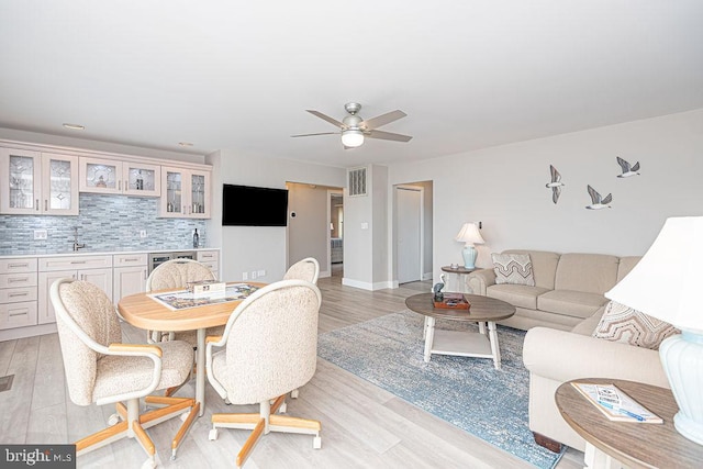 dining area with visible vents, baseboards, a ceiling fan, light wood-type flooring, and indoor wet bar