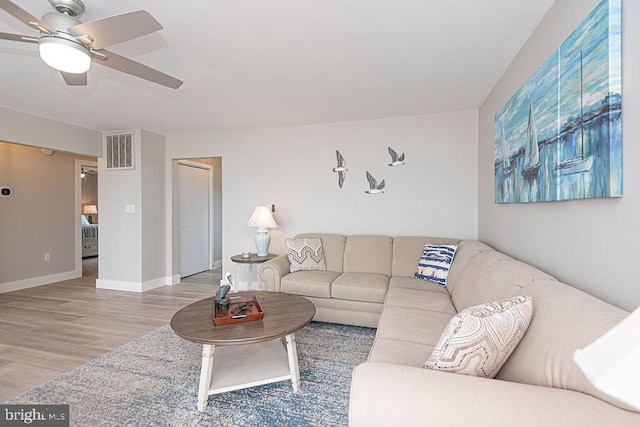 living area featuring visible vents, ceiling fan, baseboards, and wood finished floors