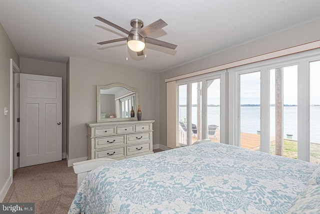 carpeted bedroom with access to outside, a water view, ceiling fan, and baseboards