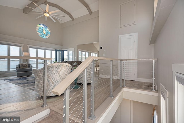 stairs with a ceiling fan, beam ceiling, high vaulted ceiling, and wood finished floors