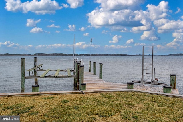 dock area featuring a water view, boat lift, and a yard