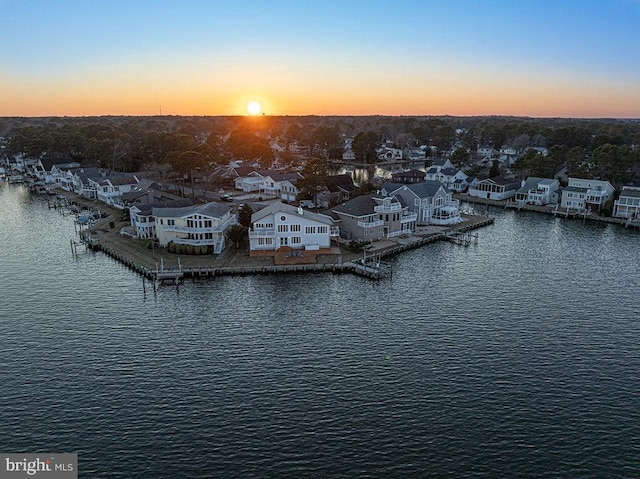 aerial view at dusk featuring a water view and a residential view