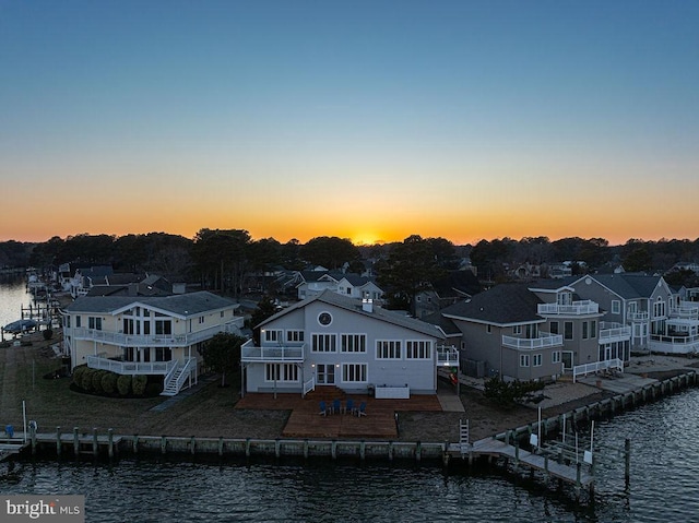 back of house at dusk featuring a water view and a residential view