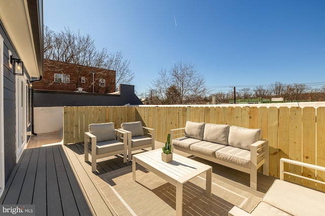 wooden terrace with an outdoor hangout area and fence