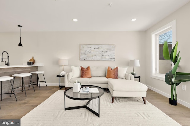 living area featuring baseboards, wood finished floors, and recessed lighting