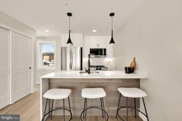 kitchen featuring stainless steel appliances, pendant lighting, backsplash, and a kitchen breakfast bar