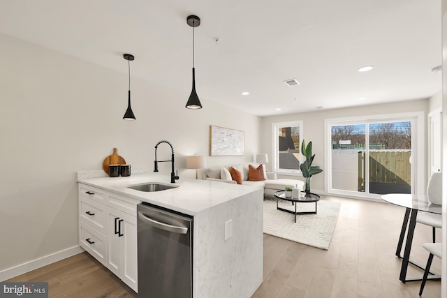 kitchen with stainless steel dishwasher, visible vents, light wood finished floors, and a sink