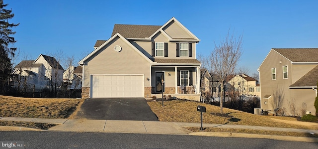 traditional-style home with a porch, a garage, stone siding, aphalt driveway, and a residential view