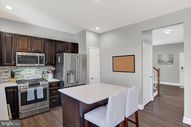 kitchen with a kitchen bar, light countertops, dark wood-style floors, and appliances with stainless steel finishes