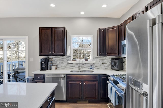 kitchen with dark brown cabinetry, stainless steel appliances, light countertops, and a sink