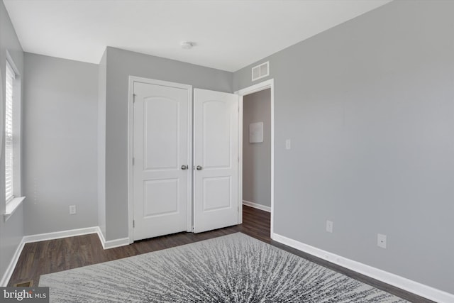 unfurnished bedroom with dark wood finished floors, visible vents, and baseboards