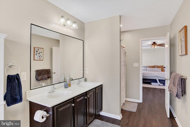 full bath featuring double vanity, wood finished floors, baseboards, and a sink