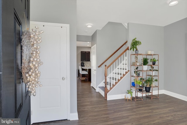 foyer featuring baseboards, wood finished floors, and stairs