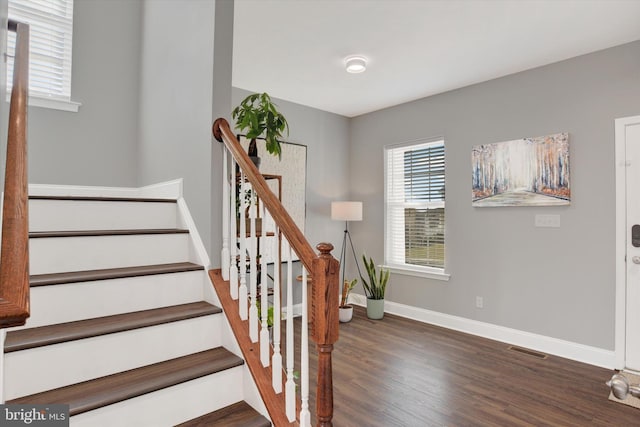 stairs featuring wood finished floors, baseboards, and visible vents