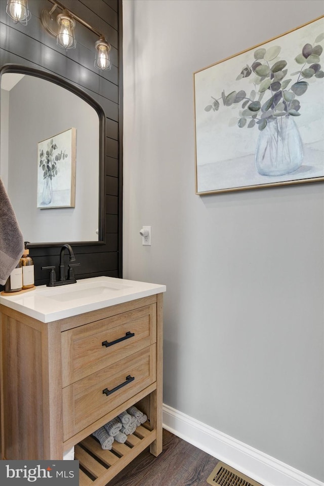 bathroom featuring vanity, visible vents, wood finished floors, and baseboards