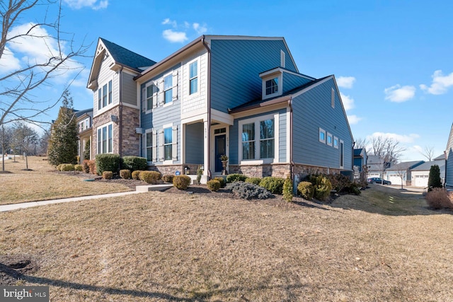 view of front of property with a porch, a front yard, and stone siding