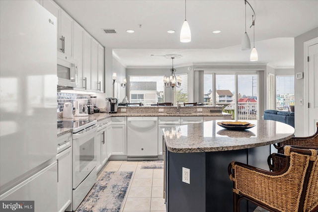 kitchen with ornamental molding, white appliances, light tile patterned flooring, and a kitchen bar