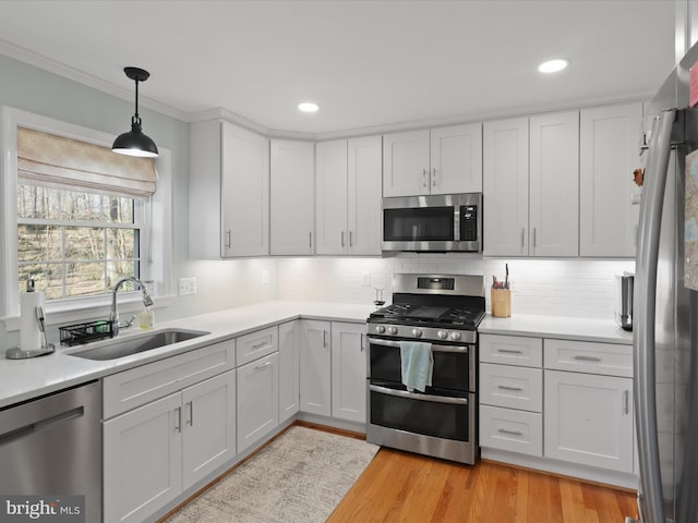 kitchen featuring light wood-style flooring, a sink, stainless steel appliances, light countertops, and decorative backsplash